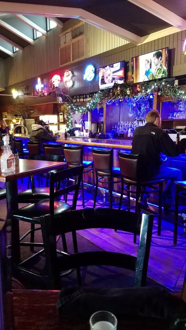 Steakhouse tables beside a TV-lit bar.